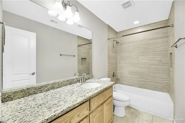 a bathroom with a granite countertop sink a toilet a mirror and shower