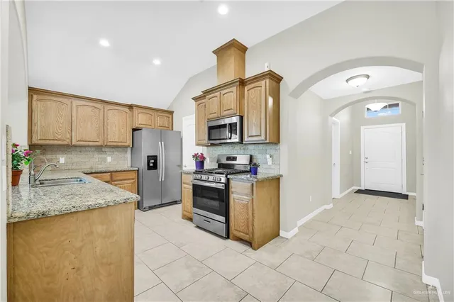 a kitchen with granite countertop a sink a stove top oven and appliances