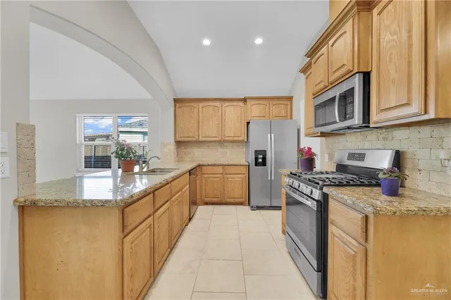 a kitchen with stainless steel appliances granite countertop a stove a sink and a microwave