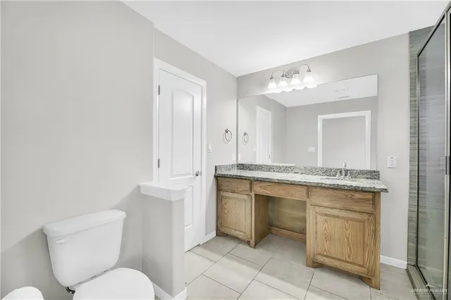 a bathroom with a granite countertop toilet sink and mirror