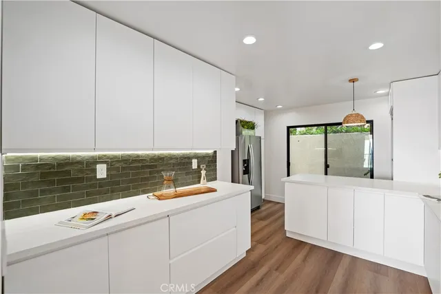 a view of a kitchen with kitchen island a sink stainless steel appliances and cabinets