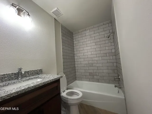 a bathroom with a granite countertop sink a toilet and bathtub