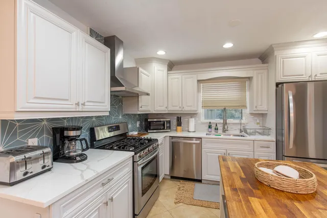 a kitchen with stainless steel appliances granite countertop a sink dishwasher stove refrigerator and cabinets