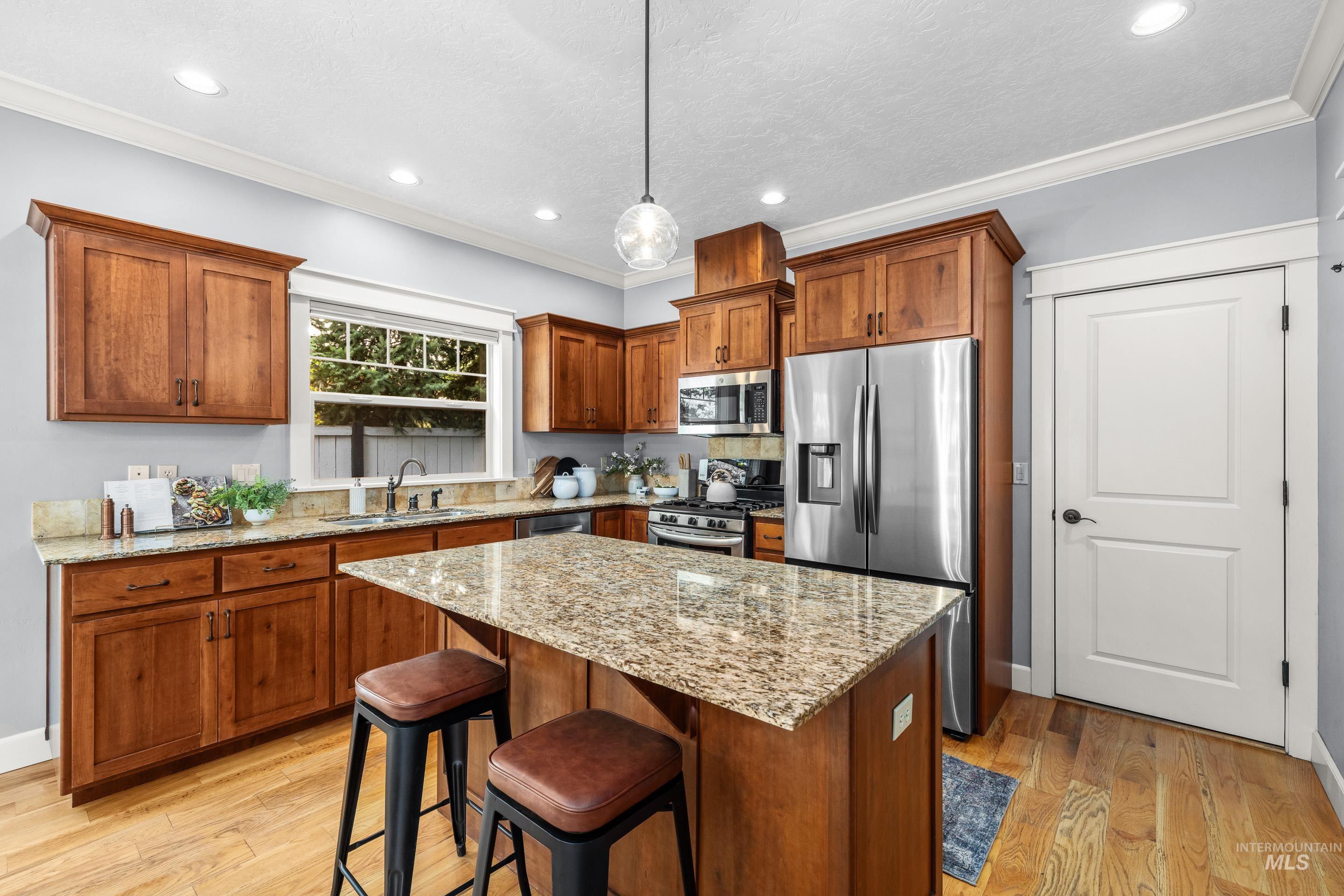 1862 West Ridenbaugh Street Boise, ID 83702 - Photo 18 of 40 Kitchen with wood cabinetry, light-toned countertops, a center island, stainless steel appliances, and wood-finish flooring