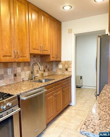 a kitchen with granite countertop cabinets stainless steel appliances and a sink