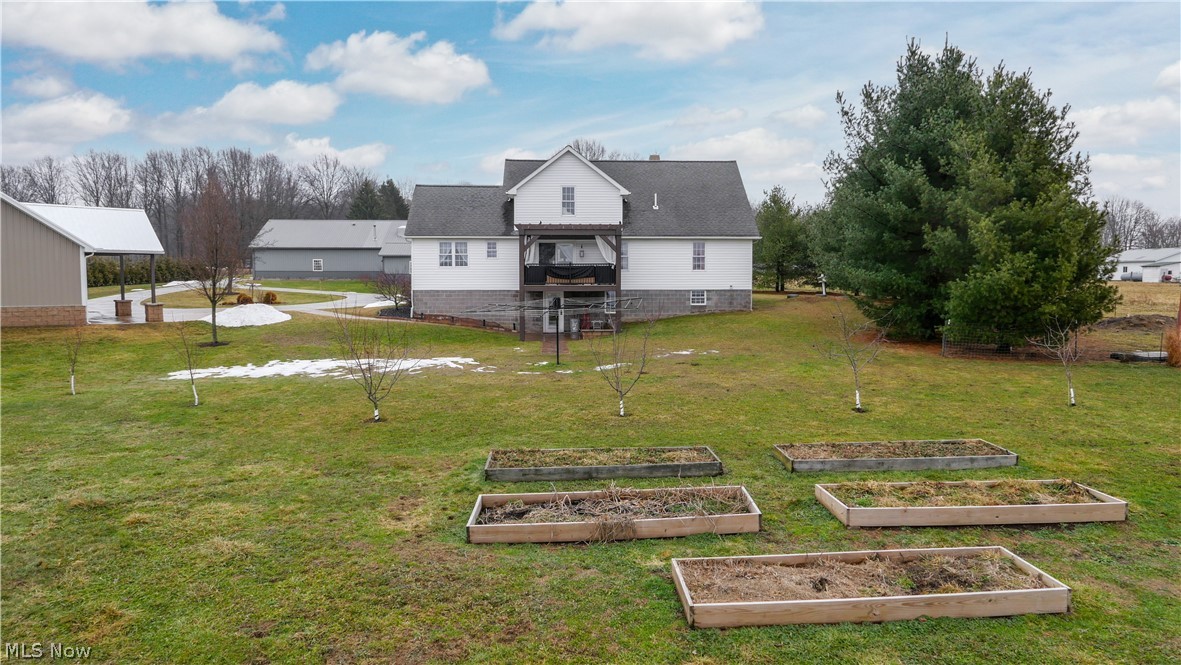 9561 Creaser Road North Bloomfield, OH 44450 - Photo 28 of 45 Rear view of property featuring a lawn, a balcony, a vegetable garden, and a shingled roof