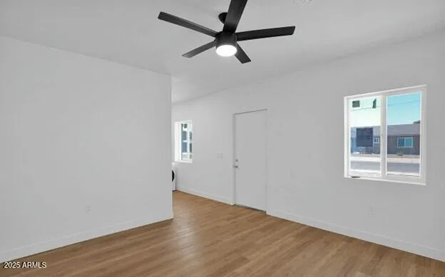 an empty room with wooden floor fan and windows
