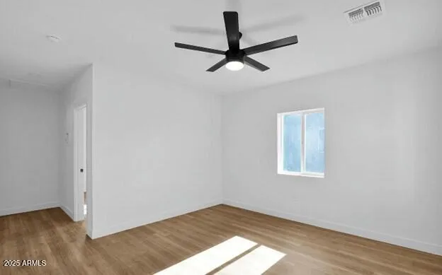 an empty room with wooden floor fan and windows