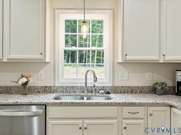 a kitchen with granite countertop a sink stainless steel appliances white cabinets and a window