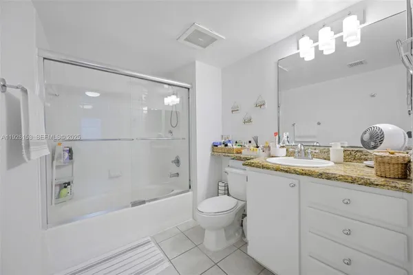 a bathroom with a granite countertop sink mirror toilet and bathtub