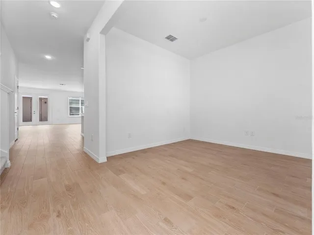 a view of a big room with wooden floor and windows