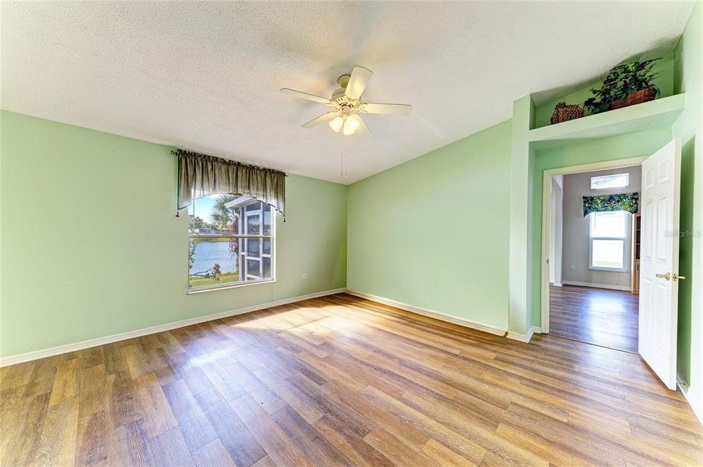 919 Spring Lakes Boulevard Bradenton, FL 34210 - Photo 21 of 43 an empty room with wooden floor chandelier fan and windows