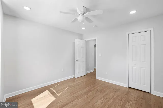 an empty room with wooden floor and ceiling fan