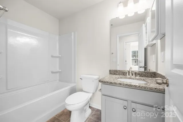 a bathroom with a granite countertop sink toilet mirror and bathtub
