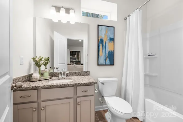 a bathroom with a granite countertop toilet sink and mirror