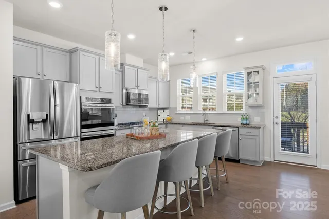 a kitchen with granite countertop a center island a sink stainless steel appliances and windows