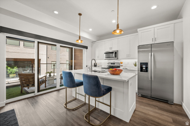 12241 900 East, Unit 7 Draper, UT 84020 - Photo 5 of 22 Modern kitchen featuring white cabinetry, stainless steel appliances, a center island with countertop seating, and wood-finish flooring
