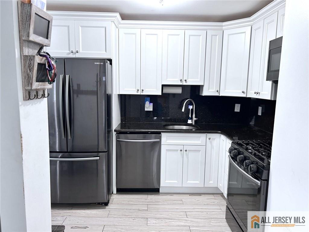 532 Cricket Lane, Unit 532 Woodbridge, NJ 07095 - Photo 7 of 14 a kitchen with a refrigerator stove and white cabinets