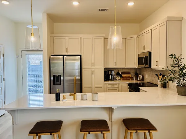 a kitchen with stainless steel appliances a refrigerator a sink and white cabinets
