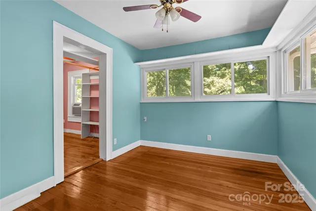 a view of an empty room with a window and wooden floor