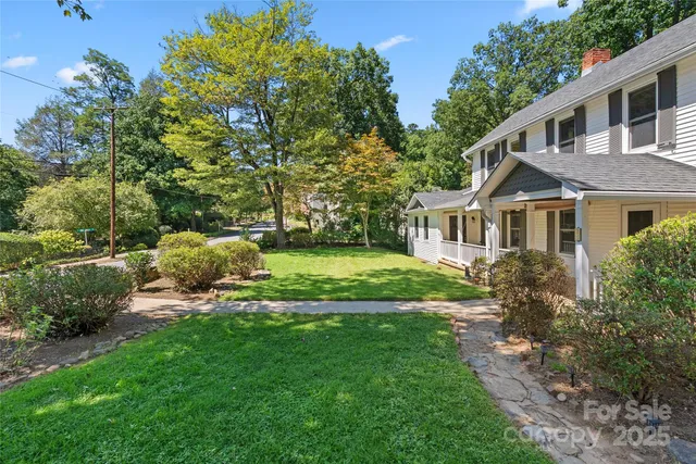 a view of a house with a big yard plants and large trees
