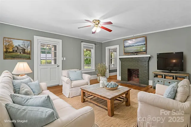 a view of an empty room with wooden floor fireplace and a window