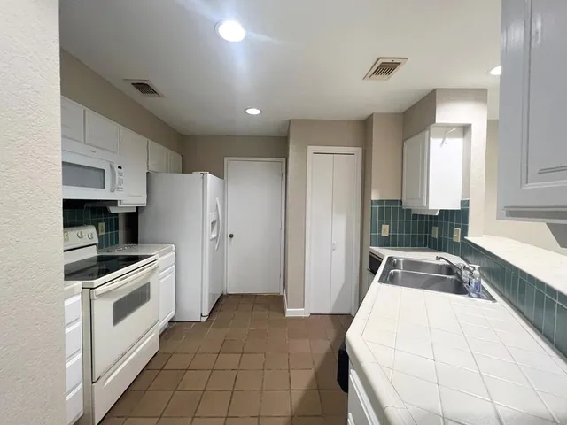 a kitchen with granite countertop a refrigerator stove and sink