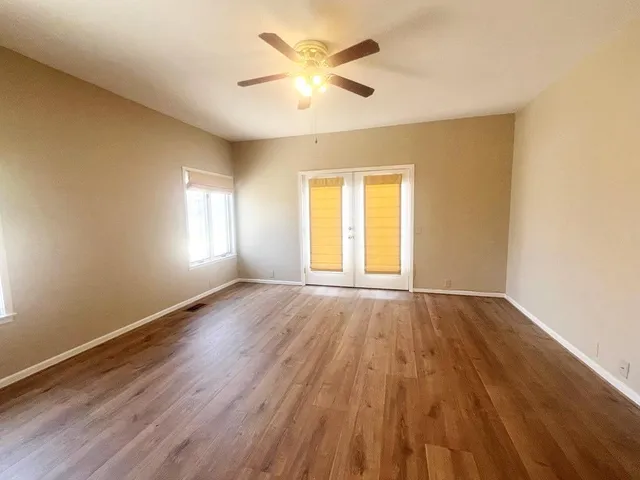 an empty room with wooden floor and windows