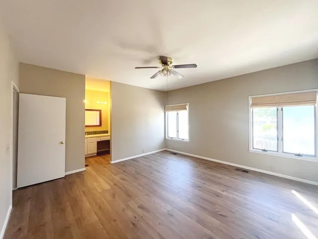 an empty room with windows and a ceiling fan