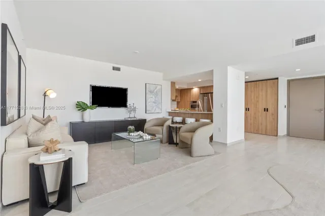 a living room with furniture a flat screen tv and kitchen view