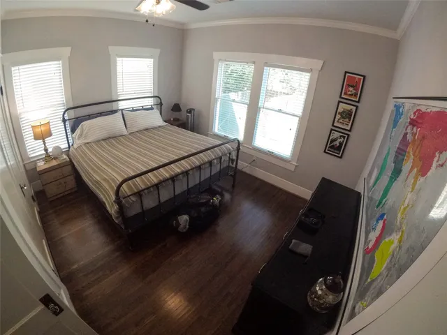 a bedroom with a bed painting on wall and a large window