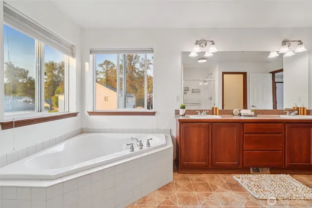 a spacious bathroom with a tub sink and mirror