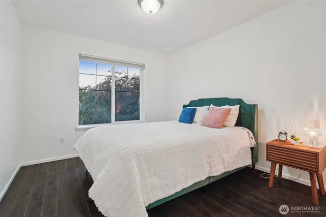 a bedroom with a bed table and two window