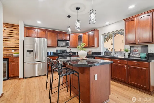 a kitchen with stainless steel appliances granite countertop a refrigerator a sink dishwasher a stove and white cabinets with wooden floor