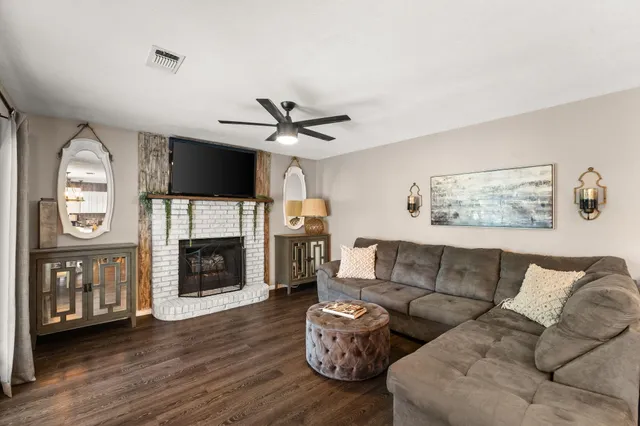 a living room with furniture kitchen view and a wooden floor