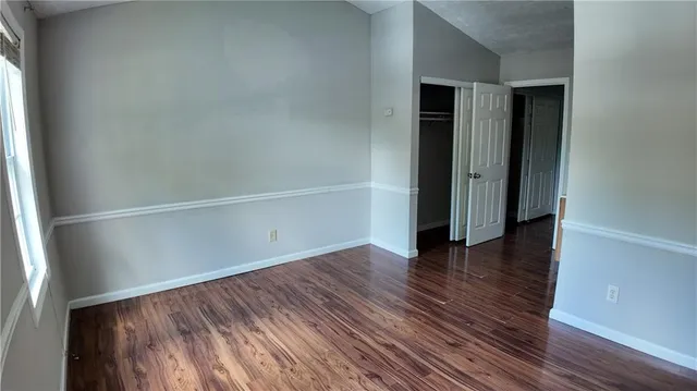 a view of an empty room with wooden floor and closet