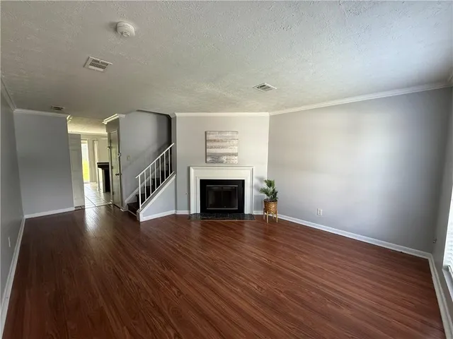 a view of an empty room with wooden floor fireplace and a window