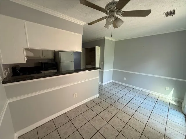 a view of a refrigerator in kitchen and an empty room