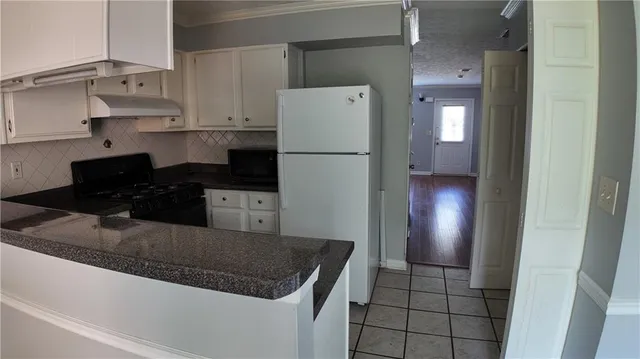 a kitchen with granite countertop a refrigerator and a stove top oven