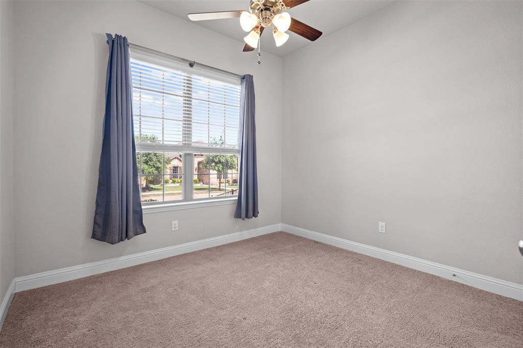 119 Happy Lane Red Oak, TX 75154 - Photo 31 of 37 Bright room featuring a large window with blinds and drapes, a ceiling fan with light fixture, light gray wall paint, and neutral-toned carpeting