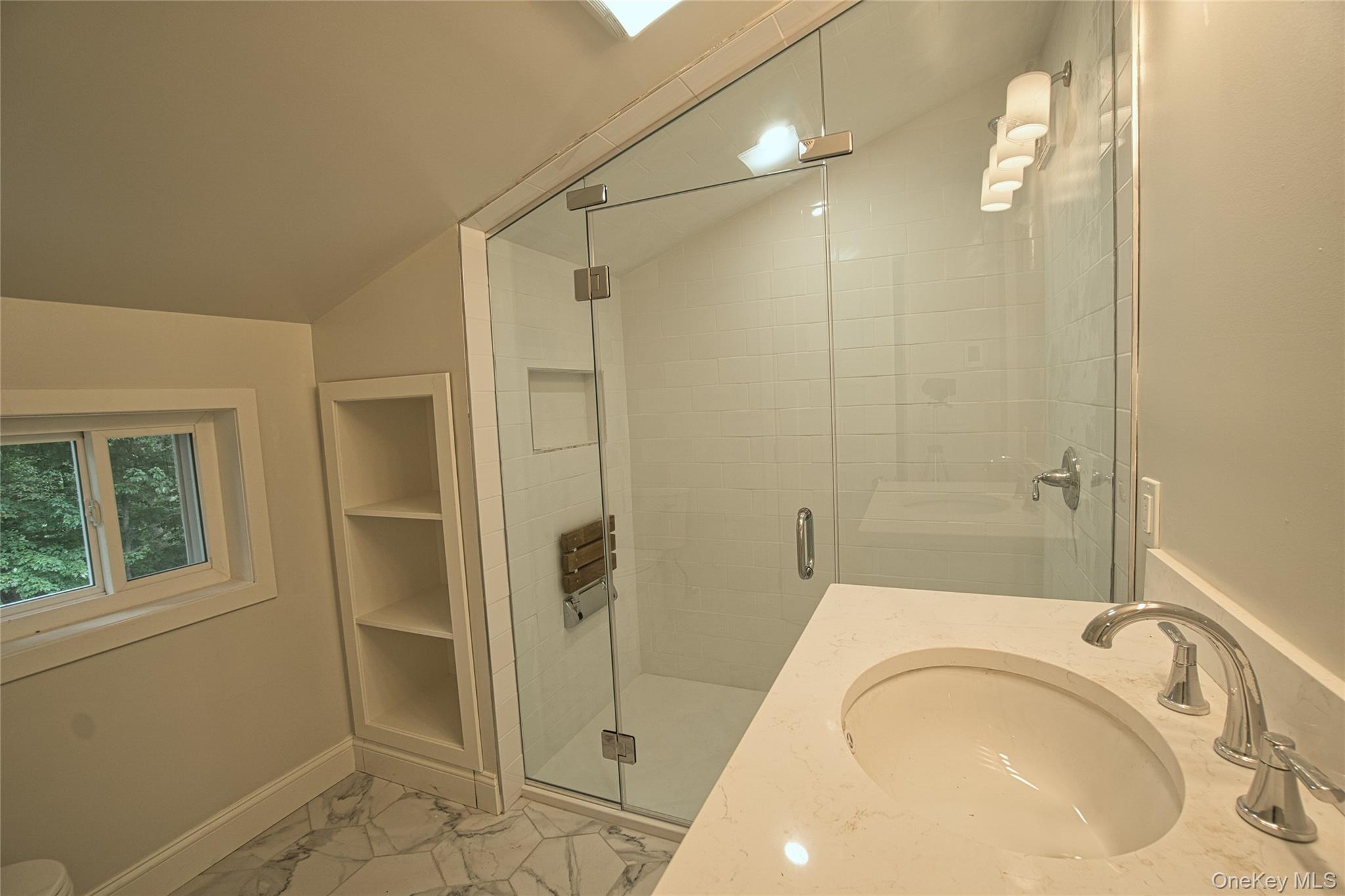 29 Overlin Road Patterson, NY 12563 - Photo 16 of 16 Contemporary bathroom featuring a clear glass walk-in shower with a built-in bench, a single vanity with an integrated sink and chrome faucet, and white tile flooring