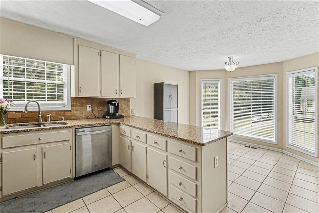 829 Dunes Way Austell, GA 30106 - Photo 10 of 28 a kitchen with granite countertop white cabinets sink and stainless steel appliances