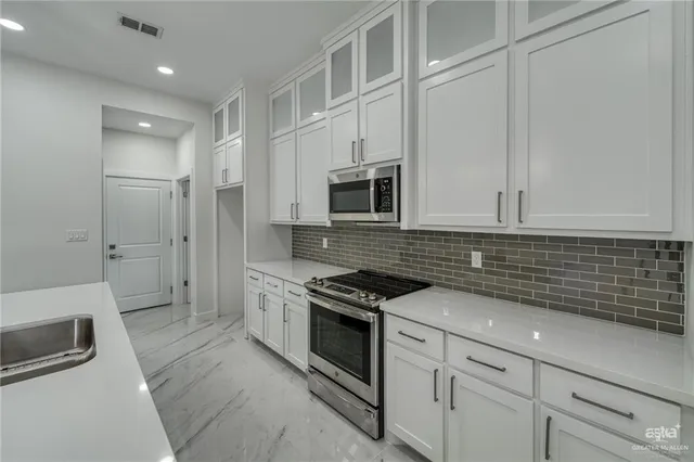 a kitchen with granite countertop white cabinets and stainless steel appliances
