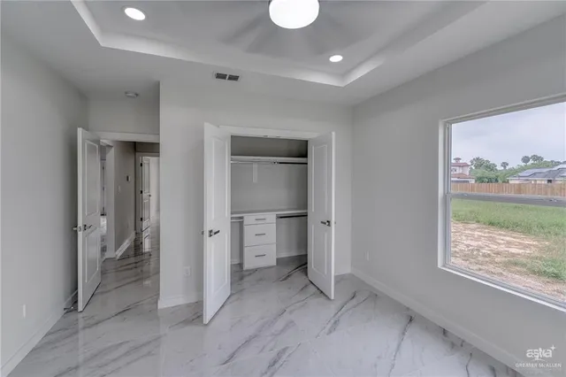 a view of an empty room with a window and a kitchen