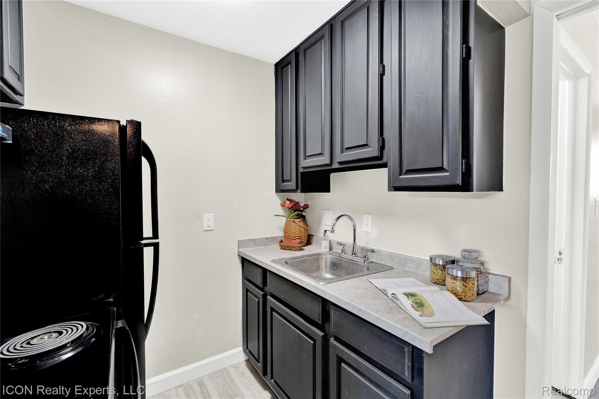 18400 Lahser Road Detroit, MI 48219 - Photo 6 of 22 Kitchen featuring light countertops, black appliances, dark cabinetry, and light wood finished floors