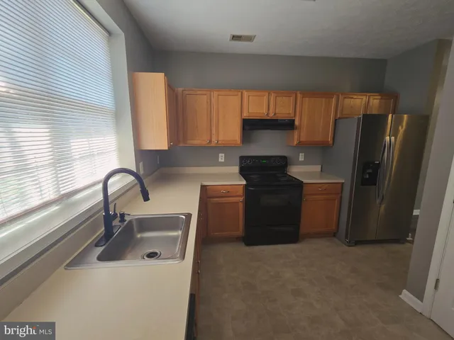 a kitchen with a sink a refrigerator and a window
