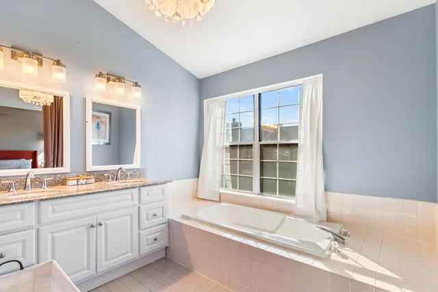 a bathroom with a granite countertop tub sink and mirror