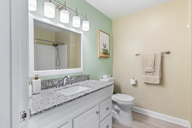 a bathroom with a granite countertop sink a toilet and a mirror