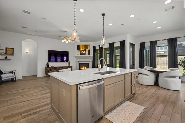 a large kitchen with a stove a sink dishwasher a dining table and chairs with wooden floor