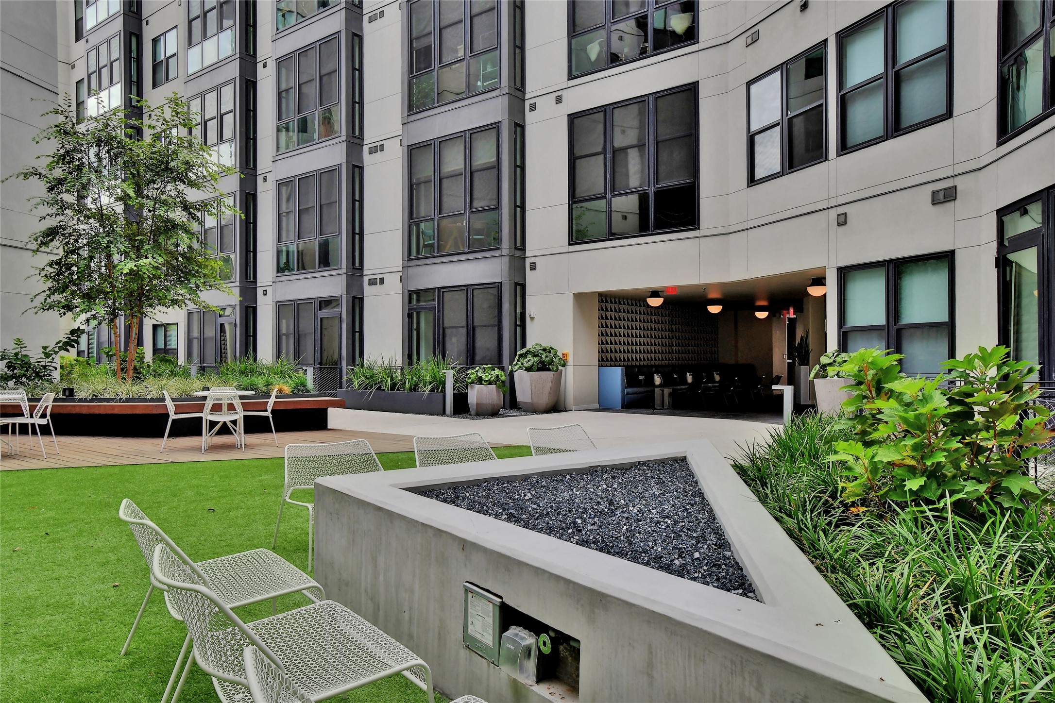 800 Embassy Drive, Unit 602 Austin, TX 78702 - Photo 27 of 37 Landscaped courtyard featuring a synthetic turf lawn, built-in concrete fire pit, and integrated planters with mature trees